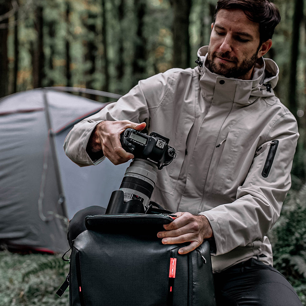Grabs  camera from the top of the OneMo 2 Backpack.